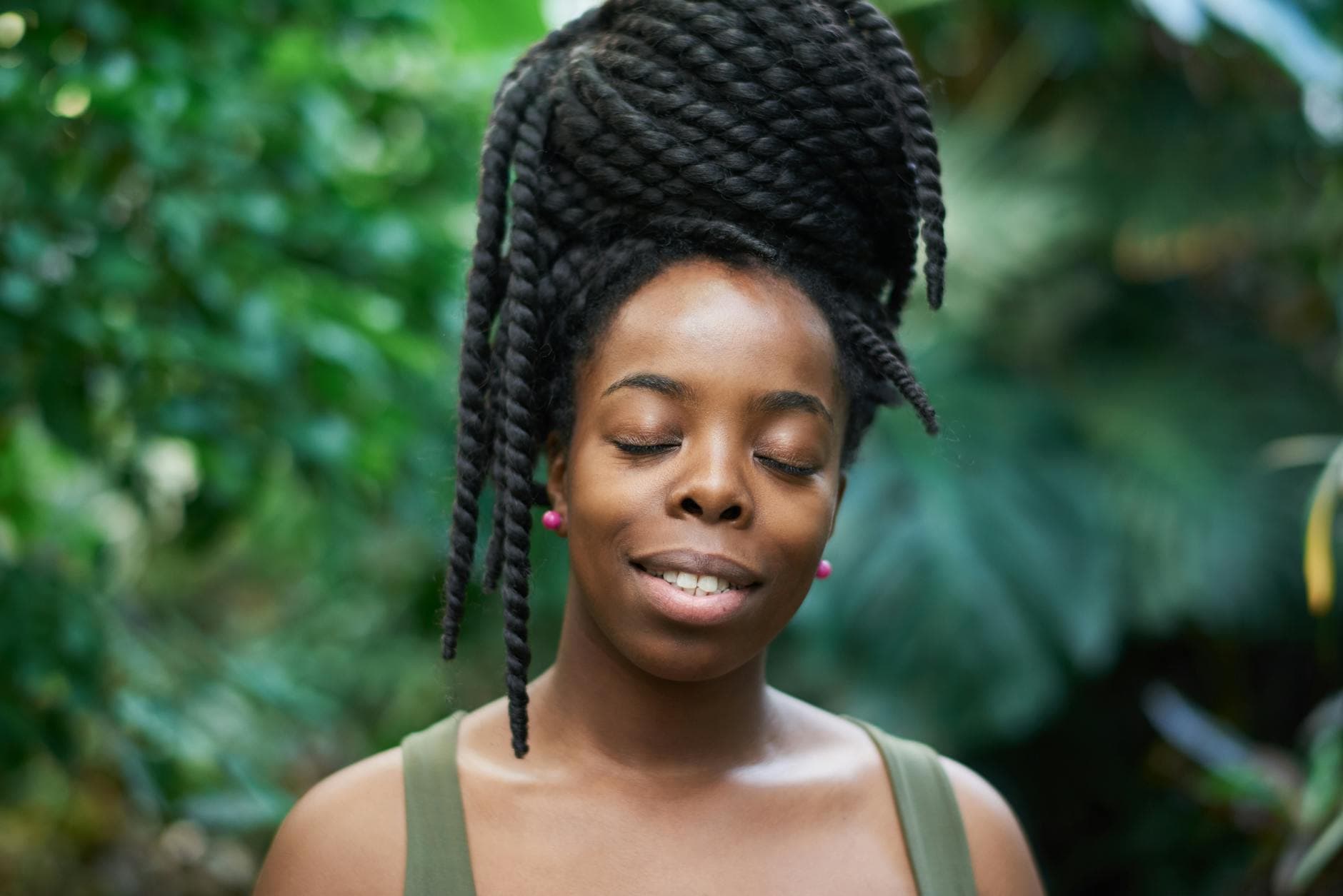 A Black woman with beautifully styled braids, showcasing a healthy hairline, smiling confidently in a well-lit outdoor setting, emphasizing the importance of edge maintenance while wearing protective styles.